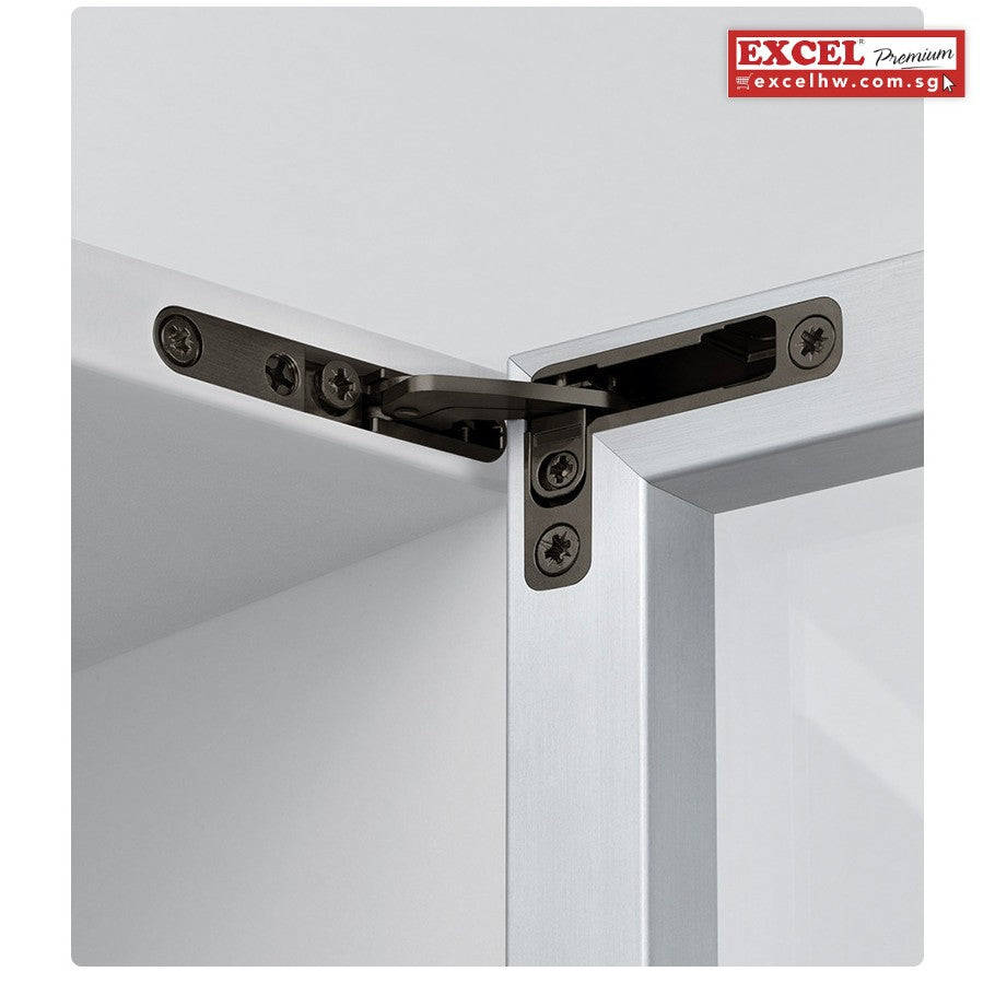 Close-up of a dark concealed top hinge fixed with screws between a cabinet top and an aluminium-framed glass door